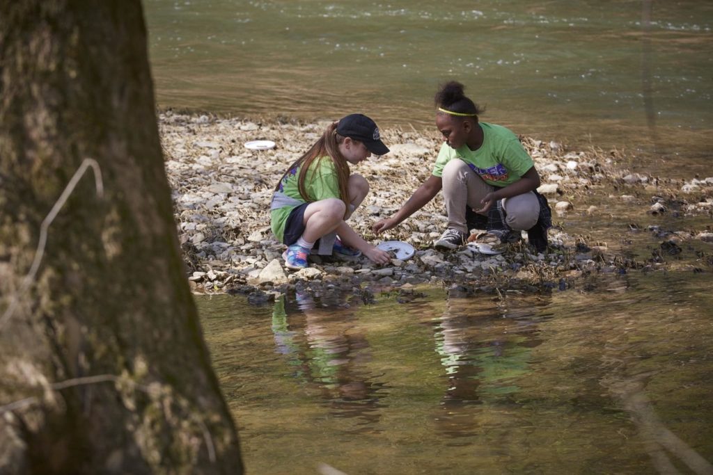 Children collect rocks next to a river
