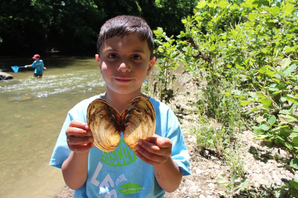 A young boy poses with a shell he found